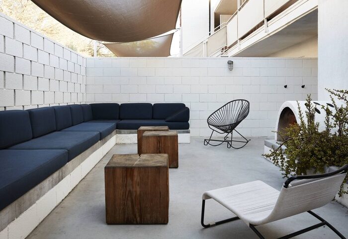 Ace Hotel & Swim Club Palm Springs patio. Modern outdoor furniture: sofa, chairs, & wood tables. Gay-friendly hotel design.