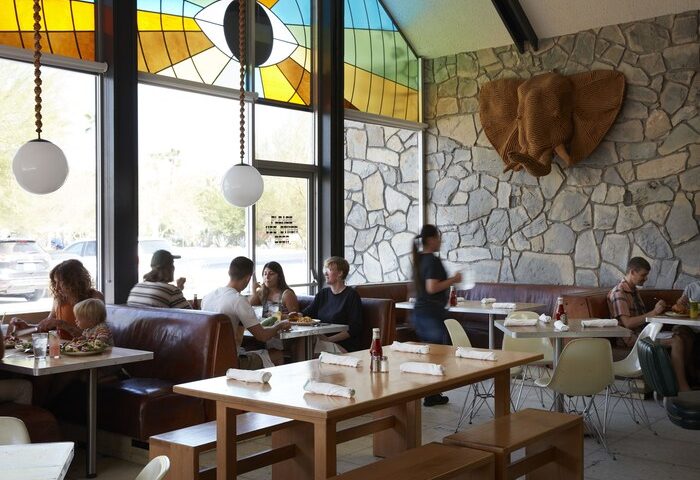 Ace Hotel and Swim Club Palm Springs restaurant interior. Gay-friendly hotel dining with stone walls, booths, and unique decor.
