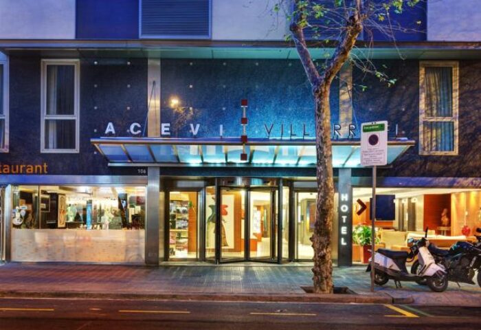 Acevi Villarroel Hotel entrance. Gay-friendly hotel in Barcelona with modern design. Scooters parked outside. Great location for gay travelers.