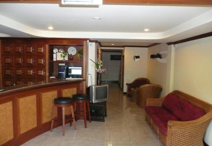 Adonis Guest House's lobby. Gay-friendly hotel with reception desk, seating area, and TV. A welcoming space for gay travelers.