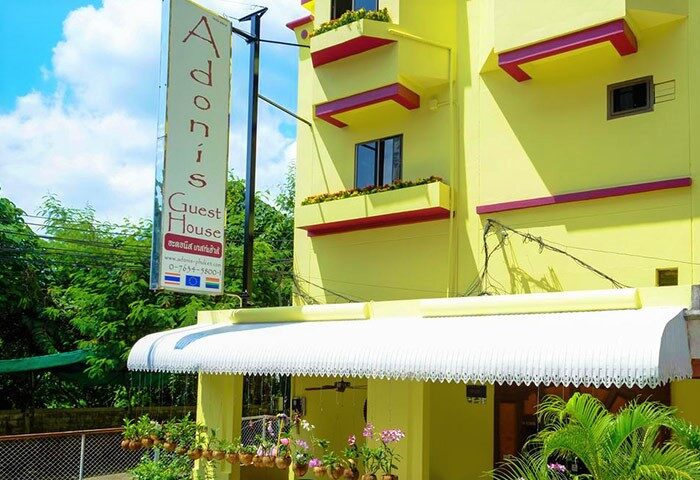 Adonis Guest House, a gay-friendly hotel in Phuket. The yellow building features flower boxes and a sign. A welcoming stay for gay travelers.