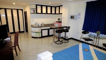 Adonis Guest House gay-friendly hotel room interior. Kitchenette, bar stools, and bed with blue and white bedding. Modern design.