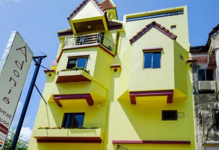Adonis Guest House, a gay-friendly hotel. Exterior view of the yellow building with a sign. A welcoming place for gay travelers.