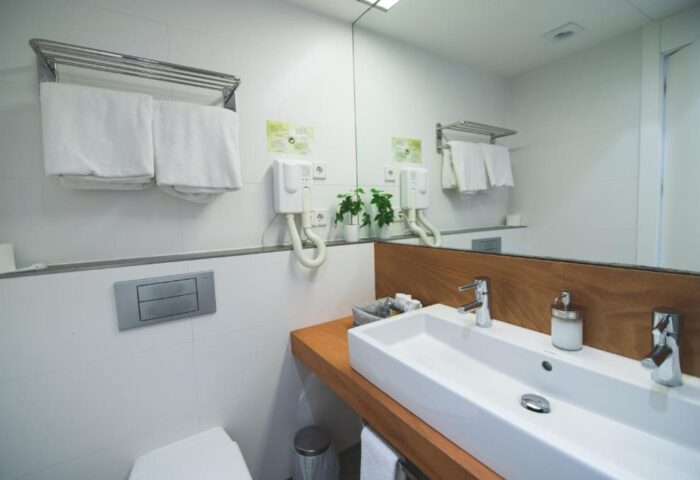 Alenti Sitges Hotel bathroom. Gay-friendly hotel with bright, modern design. Sink, mirror, and towel rack in a clean, well-lit space.