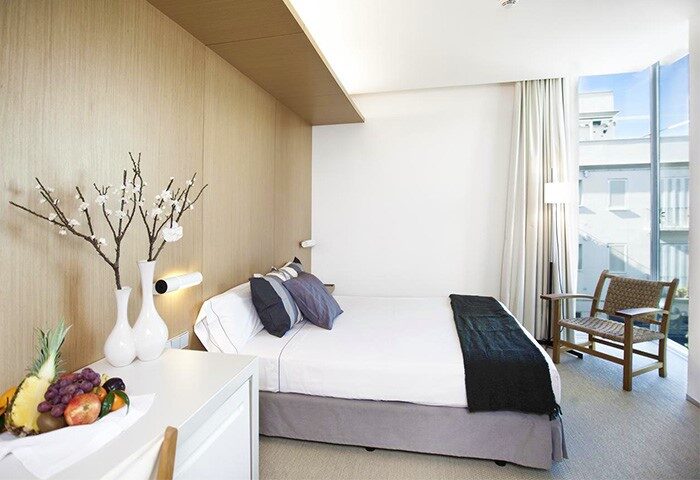 Gay-Friendly Alenti Sitges Hotel room. Modern design with fruit, flowers, and a bright window. Perfect for gay men's travel in Sitges.