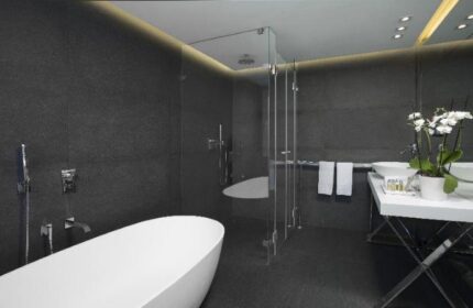 Alexander Tel Aviv Hotel's gay-friendly bathroom. Features a modern design with a white tub, glass shower, and sleek fixtures. Perfect for gay travelers.