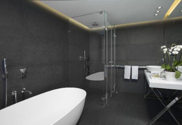 Alexander Tel Aviv Hotel's gay-friendly bathroom. Features a modern design with a white tub, glass shower, and sleek fixtures. Perfect for gay travelers.