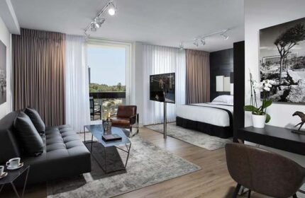 Alexander Tel Aviv Hotel gay-friendly room. Features a modern living area, balcony, and comfortable bed. Perfect for gay travelers in Tel Aviv.