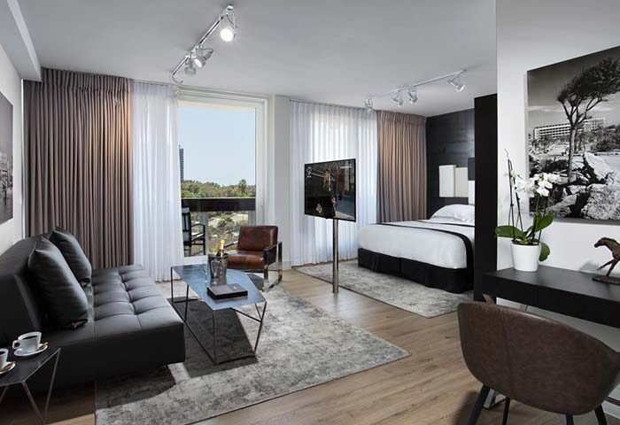 Alexander Tel Aviv Hotel gay-friendly room. Features a modern living area, balcony, and comfortable bed. Perfect for gay travelers in Tel Aviv.