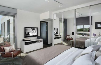 Alexander Hotel Tel Aviv room. Gay-friendly hotel featuring a modern bedroom with mirrored closet, balcony, and TV. Ideal for gay travel.