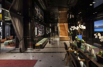 Alexander Tel Aviv Hotel lobby. Gay-friendly hotel with modern design, dark walls, staircase, seating area, and stylish decor. Upscale travel.