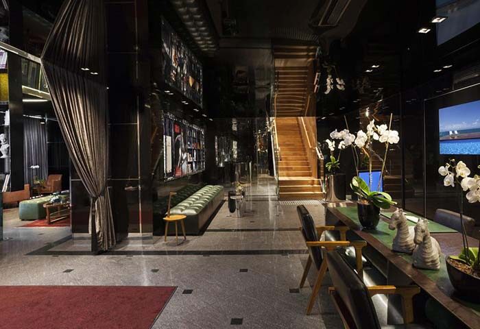 Alexander Tel Aviv Hotel lobby. Gay-friendly hotel with modern design, dark walls, staircase, seating area, and stylish decor. Upscale travel.