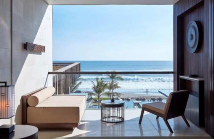Alila Seminyak, a gay-friendly hotel. Balcony view of the ocean, palm trees, and beach. Relaxing travel destination for gay men.