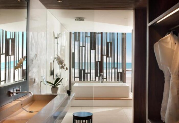 Alila Seminyak's luxurious bathroom with ocean view. This gay-friendly hotel offers a stylish retreat in Bali. Modern design, bathtub, robes.