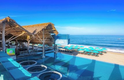 Almar Resort, a luxury LGBT beach front hotel, adults only. View of the pool, beach, ocean, and thatched roof bar. Gay-friendly hotel.