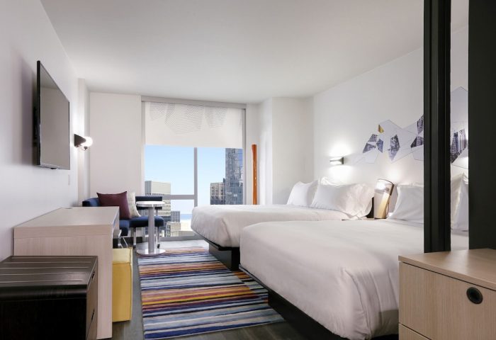 Aloft Chicago Mag Mile hotel room. Gay-friendly hotel with two beds, colorful rug, and city view. Modern design. Chicago travel for gay men.