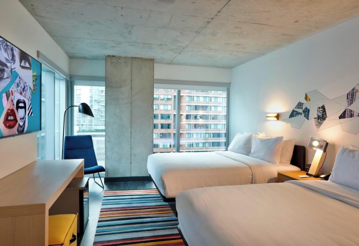 Aloft Chicago Mag Mile hotel room. Modern design, two beds, city view. Gay-friendly hotel, colorful rug.