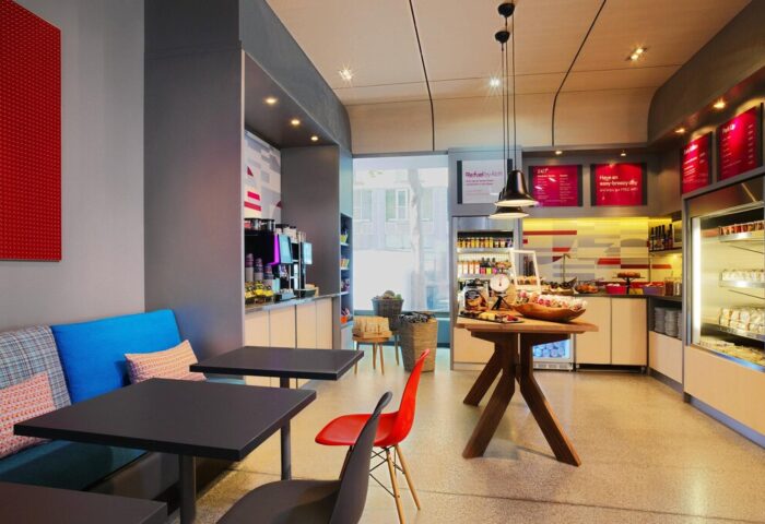Aloft Munich's Refuel cafe, a gay-friendly hotel. Modern interior with tables, seating, and a snack bar. Perfect for gay men traveling.