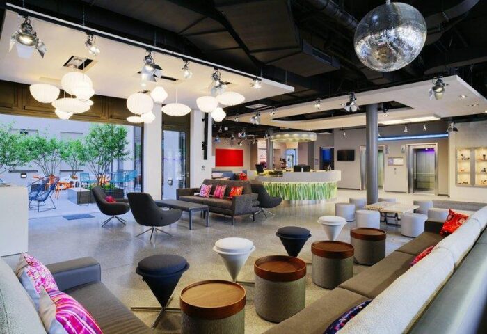Lobby view at Aloft Munich, a gay-friendly hotel. Modern design with seating areas, a disco ball, and a vibrant reception desk. Great for gay travel.