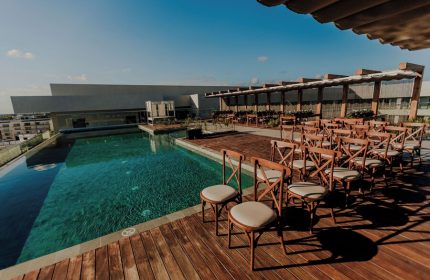 Aloft Playa del Carmen gay-friendly hotel rooftop pool and event space. Chairs are aligned on the wooden deck, ready for a wedding or special event.