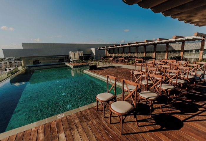 Aloft Playa del Carmen gay-friendly hotel rooftop pool and event space. Chairs are aligned on the wooden deck, ready for a wedding or special event.