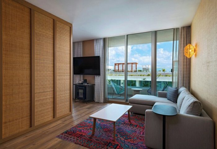Aloft Playa del Carmen gay-friendly hotel room. Modern decor, balcony with ocean view. Comfy seating, TV, and stylish design. Perfect for gay travel.