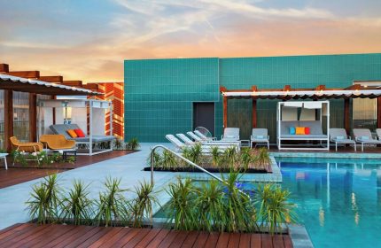 Rooftop pool at Aloft Playa del Carmen, a gay-friendly hotel. Loungers, daybeds, and vibrant decor create a stylish, welcoming atmosphere.