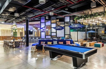 Aloft Tulum, a gay-friendly hotel. Interior view of the hotel lobby with a pool table, bar, and seating areas. Modern design and decor.
