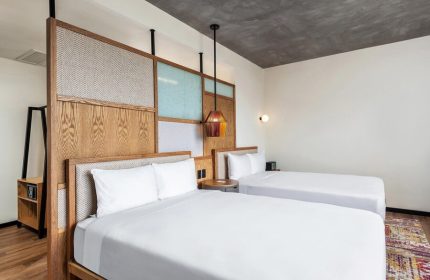 Aloft Tulum hotel room with two beds. Gay-friendly hotel with modern design, wooden headboard, and colorful accents. Great for gay travel.