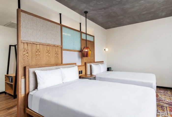 Aloft Tulum hotel room with two beds. Gay-friendly hotel with modern design, wooden headboard, and colorful accents. Great for gay travel.