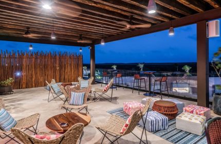 Aloft Tulum, a gay-friendly hotel, features a stylish rooftop lounge with chairs, bar stools, and scenic views. Perfect for gay travelers.