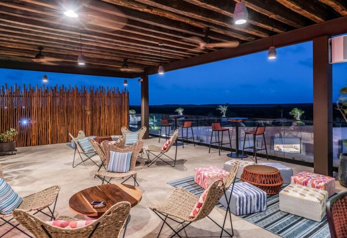Aloft Tulum, a gay-friendly hotel, features a stylish rooftop lounge with chairs, bar stools, and scenic views. Perfect for gay travelers.