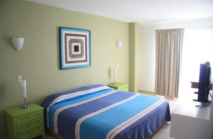Amapas Apartments Puerto Vallarta gay-friendly hotel room. Blue striped bed, green nightstands, and modern art. Comfortable stay for gay travelers.