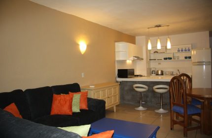 Amapas Apartments Puerto Vallarta living space. Gay-friendly hotel with kitchen, bar stools, couch, and dining table. Interior design.