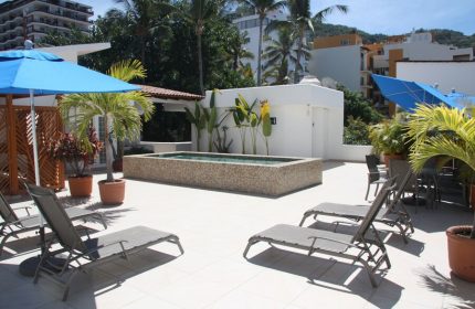 Rooftop pool and lounge at Amapas Apartments, a gay-friendly hotel in Puerto Vallarta. Features lounge chairs, umbrellas, and tropical plants.