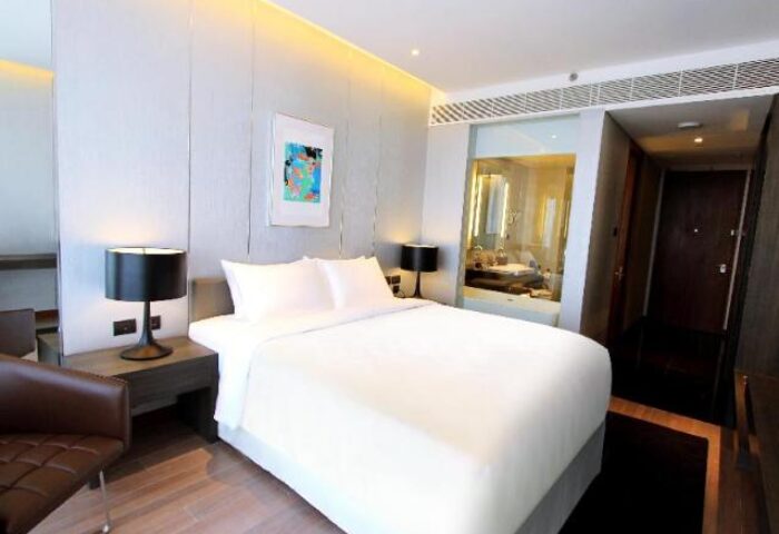 Amara Bangkok Hotel room. Gay-friendly hotel with a bed, lamps, and a view of the bathroom. Modern design. Perfect for gay travelers.