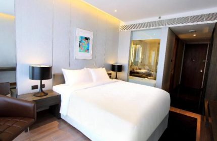 Amara Bangkok Hotel room. Gay-friendly hotel with a bed, lamps, and a view of the bathroom. Modern design. Perfect for gay travelers.
