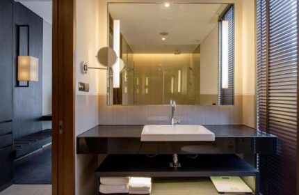 Amara Bangkok Hotel's gay-friendly bathroom. Modern design with a large mirror, sleek sink, and minimalist fixtures. Ideal for gay travelers.