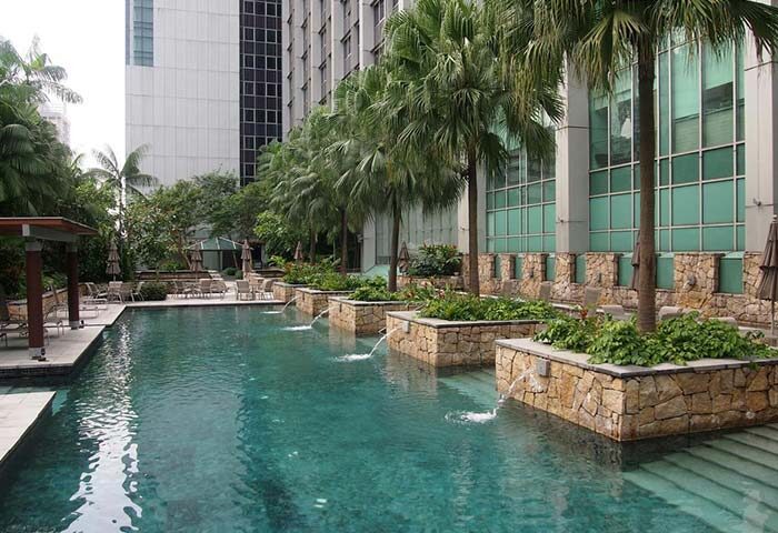 Amara Singapore gay-friendly hotel pool. Lush greenery and palm trees surround the pool, creating a relaxing oasis for gay travelers.