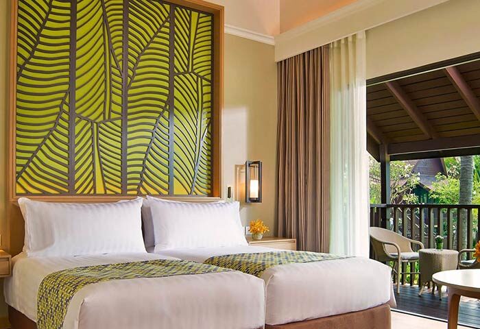 Amari Koh Samui gay-friendly hotel room with twin beds, leaf design headboard, balcony, and outdoor seating. Perfect for gay travel.