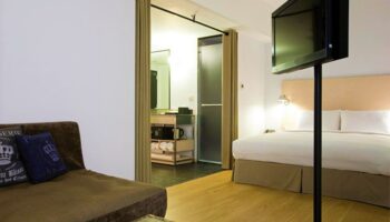 Amba Taipei Ximending Gay-Friendly Hotel room. Features a bed, sofa, TV, and bathroom. Ideal for gay travelers seeking style & comfort.