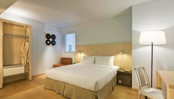 Amba Taipei Ximending gay-friendly hotel room. Queen bed, desk, closet, and decor. Modern design, comfortable for gay travelers in Taipei's Ximending.