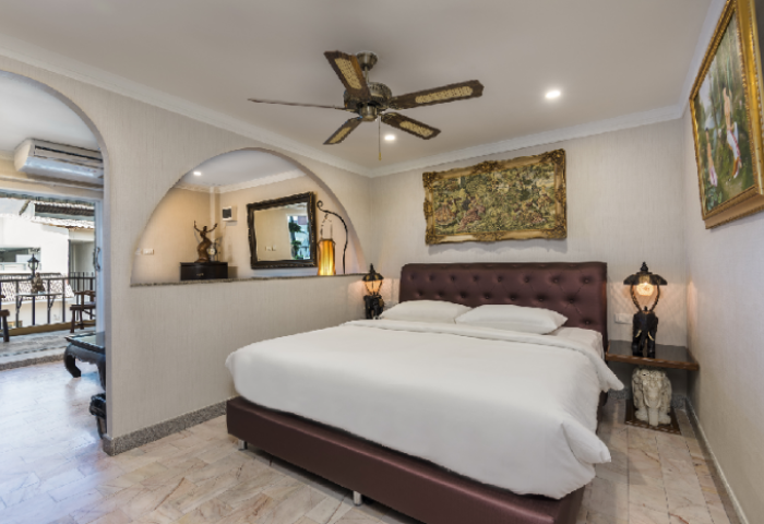 Ambiance Pattaya Hotel gay-friendly room. Features a bed, ceiling fan, balcony access, and ornate decor. Ideal for gay travel in Thailand.