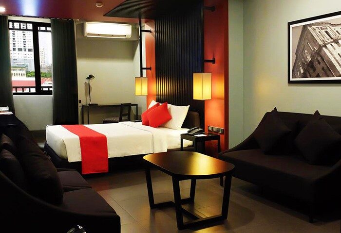 Amelie Hotel Manila gay-friendly room. Modern design with a bed, sofas, desk, and city view. Comfortable stay for gay travelers in Manila.