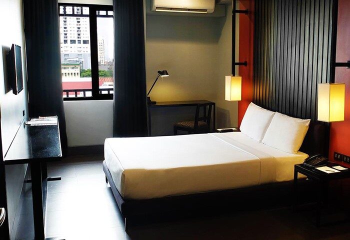Amelie Hotel Manila room. Gay-friendly hotel with a bed, desk, and city view. Modern design. Perfect for gay men's travel in Manila, Philippines.