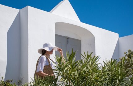 Amelot Art Suites: Woman in hat at gay-friendly hotel. White building, blue sky. Ideal for gay travel.
