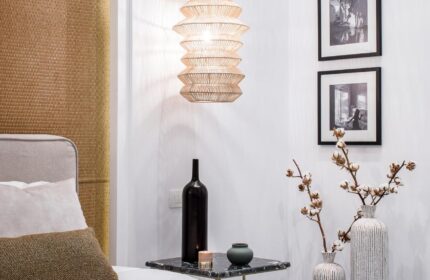Amelot Art Suites gay-friendly hotel room. Bedside table with vases, bottles, and framed art. Modern lighting. Stylish gay travel lodging.