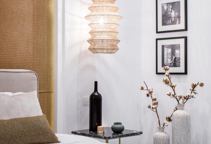 Amelot Art Suites gay-friendly hotel room. Bedside table with vases, bottles, and framed art. Modern lighting. Stylish gay travel lodging.