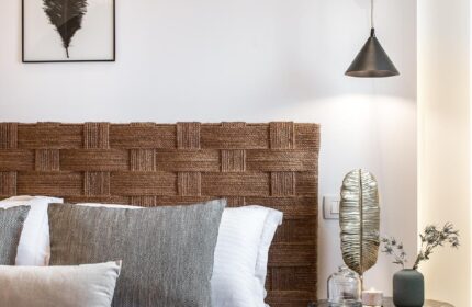 Amelot Art Suites gay-friendly hotel room. Woven headboard, feather art, side table with decor. Stylish design for gay travelers.