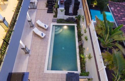 Amerta Seminyak gay-friendly hotel aerial view. Pool, lounge chairs, and Balinese statues. A perfect gay travel destination in Seminyak.